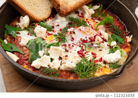 Pan of middle eastern dish shakshuka with toasts Pan of middle eastern dish shakshuka with toasts 112321038