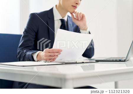 書類の内容を調べるビジネスマン 112321320
