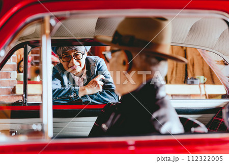 愛車越しに会話をしているシニア夫婦の写真 112322005