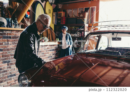 愛車を見ながら会話をしているシニア夫婦の写真 112322020