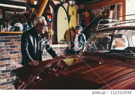 愛車を見ながら会話をしているシニア夫婦の写真 112322036