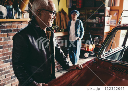 愛車を見ながら会話をしているシニア夫婦の写真 112322043