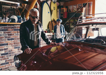 愛車を見ながら会話をしているシニア夫婦の写真 112322056