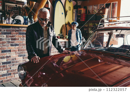 愛車を見ながら会話をしているシニア夫婦の写真 112322057