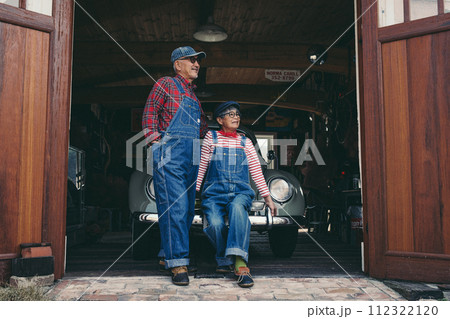 ガレージ前で愛車と佇むシニア夫婦のファッション写真 112322120