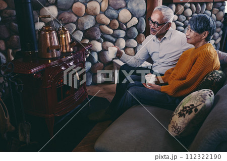 仲睦まじくソファーに座っているシニア夫婦の写真 112322190