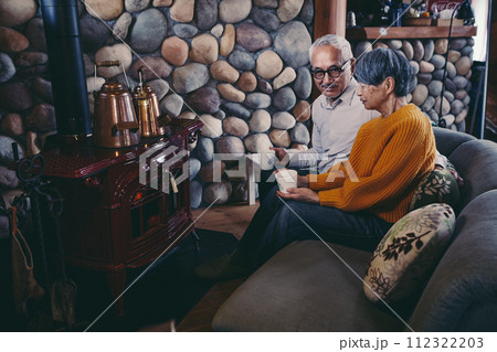 仲睦まじくソファーに座っているシニア夫婦の写真 仲睦まじくソファーに座っているシニア夫婦の写真 112322203
