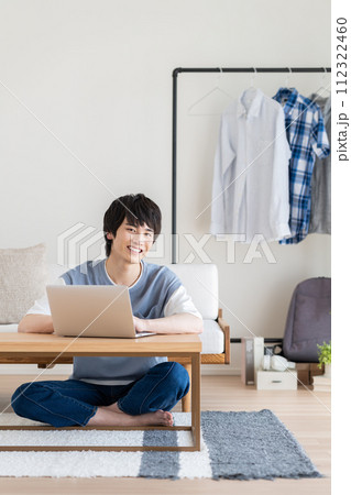 リビングでパソコンを使う若い男性 112322460