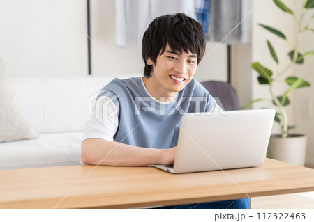 リビングでパソコンを使う若い男性 112322463