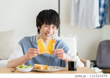 リビングで朝食を食べる若い男性 112322479