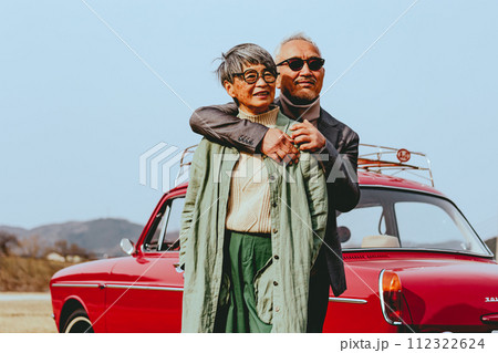 愛車バックに寄り添うシニア夫婦の写真 112322624