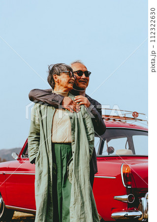 愛車バックに寄り添うシニア夫婦の写真 112322630