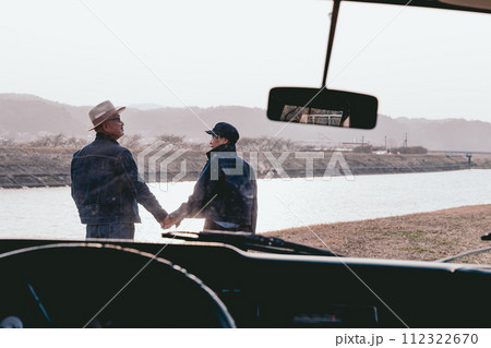 夕暮れで手を繋ぐシニア夫婦の写真 112322670