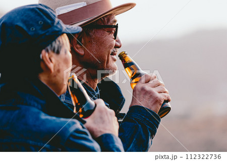 夕日を見ながら佇むシニア夫婦の写真 112322736
