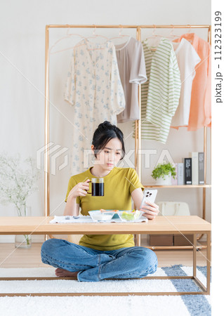 リビングで朝食を食べる若い女性 112323199