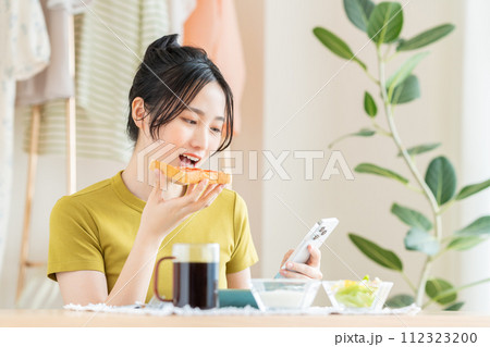 リビングで朝食を食べる若い女性 リビングで朝食を食べる若い女性 112323200