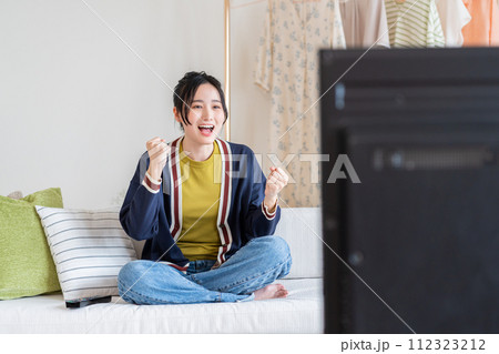 リビングでテレビを見る若い女性 リビングでテレビを見る若い女性 112323212