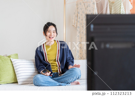 リビングでテレビを見る若い女性 リビングでテレビを見る若い女性 112323213