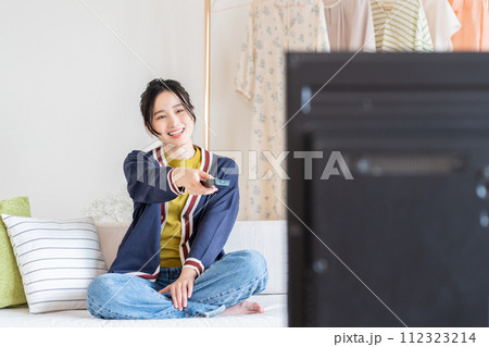 リビングでテレビを見る若い女性 112323214