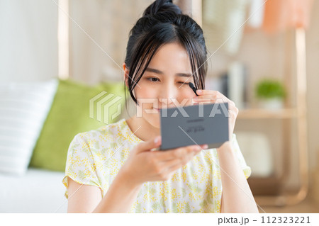アイメイクをする若い女性 アイメイクをする若い女性 112323221