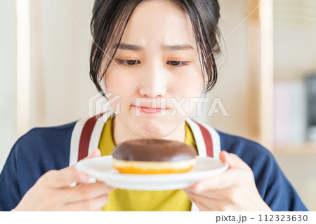 リビングでドーナツを食べる若い女性 112323630