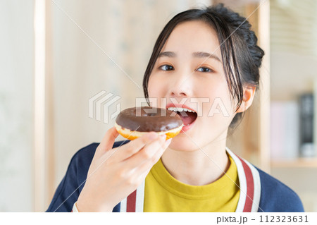 リビングでドーナツを食べる若い女性 112323631