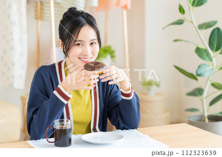 リビングでドーナツを食べる若い女性 リビングでドーナツを食べる若い女性 112323639