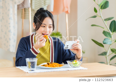 リビングでパスタを食べる若い女性 112323663