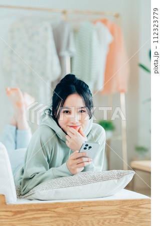 リビングでスマホを見る若い女性 112323779