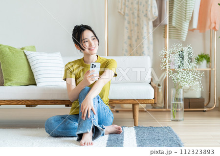 リビングでスマホを見る若い女性 112323893