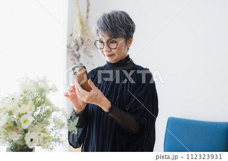 花瓶の花を撮影するシニア女性 112323931