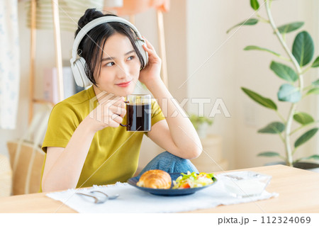 リビングで朝食を食べる若い女性 112324069
