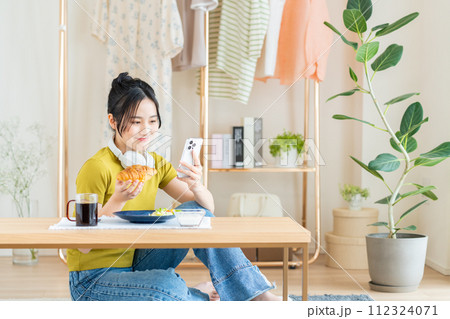 リビングで朝食を食べる若い女性 112324071