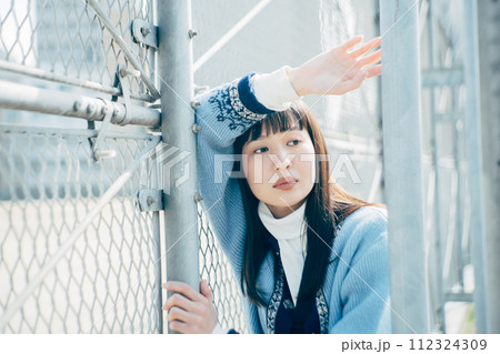 フェンスにもたれる女性 112324309