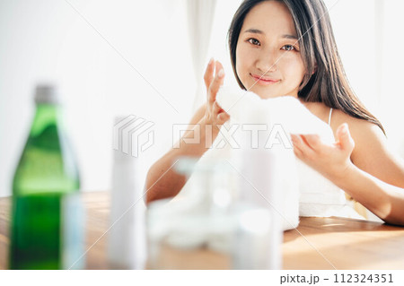 朝の日差しを浴びながらスキンケアする女性 112324351
