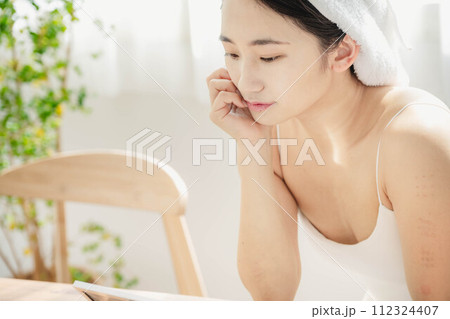 朝の窓際でスキンケアをする若い女性 112324407