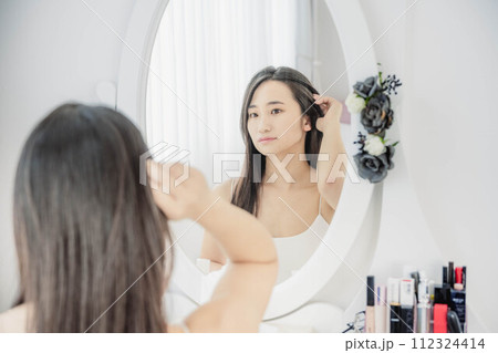 鏡を見ながらスキンケアする若い女性 112324414