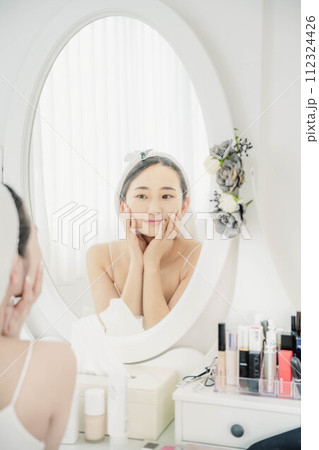 鏡を見ながらスキンケアする若い女性 112324426