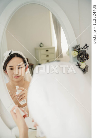 鏡を見ながらスキンケアする若い女性 鏡を見ながらスキンケアする若い女性 112324438