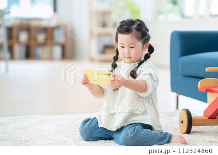 リビングでスマホで遊ぶ女の子 112324860