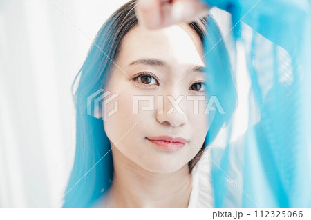 青い布の隙間から顔を覗かせる女性 112325066