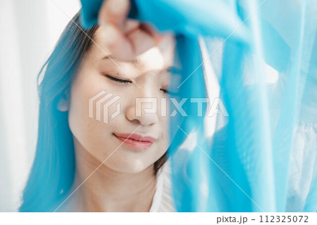 青い布の隙間から顔を覗かせる女性 112325072