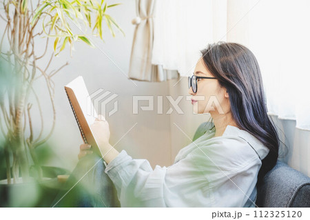 ソファーに座って読書をする女性 112325120