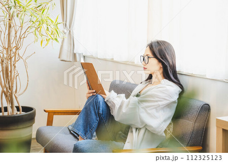 ソファーに座って読書をする女性 112325123