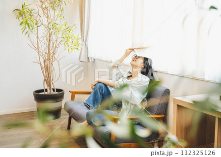 ソファーで読書の休憩をする女性 112325126