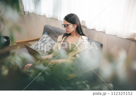ソファーでテレワークする女性 ソファーでテレワークする女性 112325152