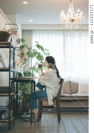 部屋でパソコンと本を広げ仕事する女性 部屋でパソコンと本を広げ仕事する女性 112325171