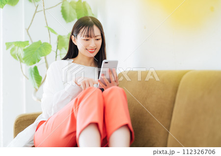 ソファでスマホを見る女性 112326706