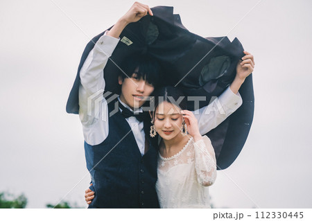 屋外で雨の中寄り添う男女 112330445