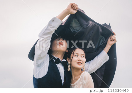 屋外で雨の中寄り添う男女 112330449